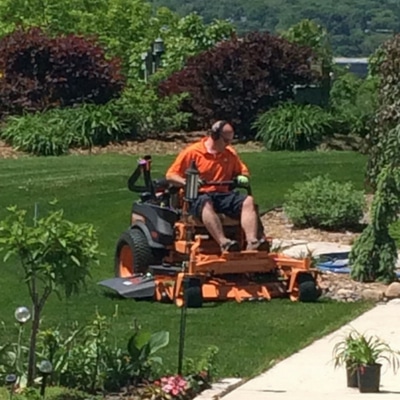 Jeremy Bruce, the owner of Midwest Lawn Pro riding a commercial mower on a customer lawn.